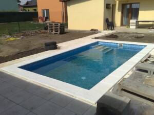 Bazénový lem rohový bílý, umístěný u obdélného bazénu.